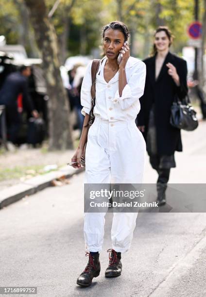 Model is seen wearing a white shirt and pants and. Brown red laced boots outside the Miu Miu show during the Womenswear Spring/Summer 2024 as part of...