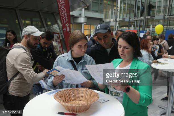 Russian-speaking stand hostess speaks with a couple from Ukraine at a jobs fair for migrants and refugees on October 04, 2023 in Berlin, Germany. The...