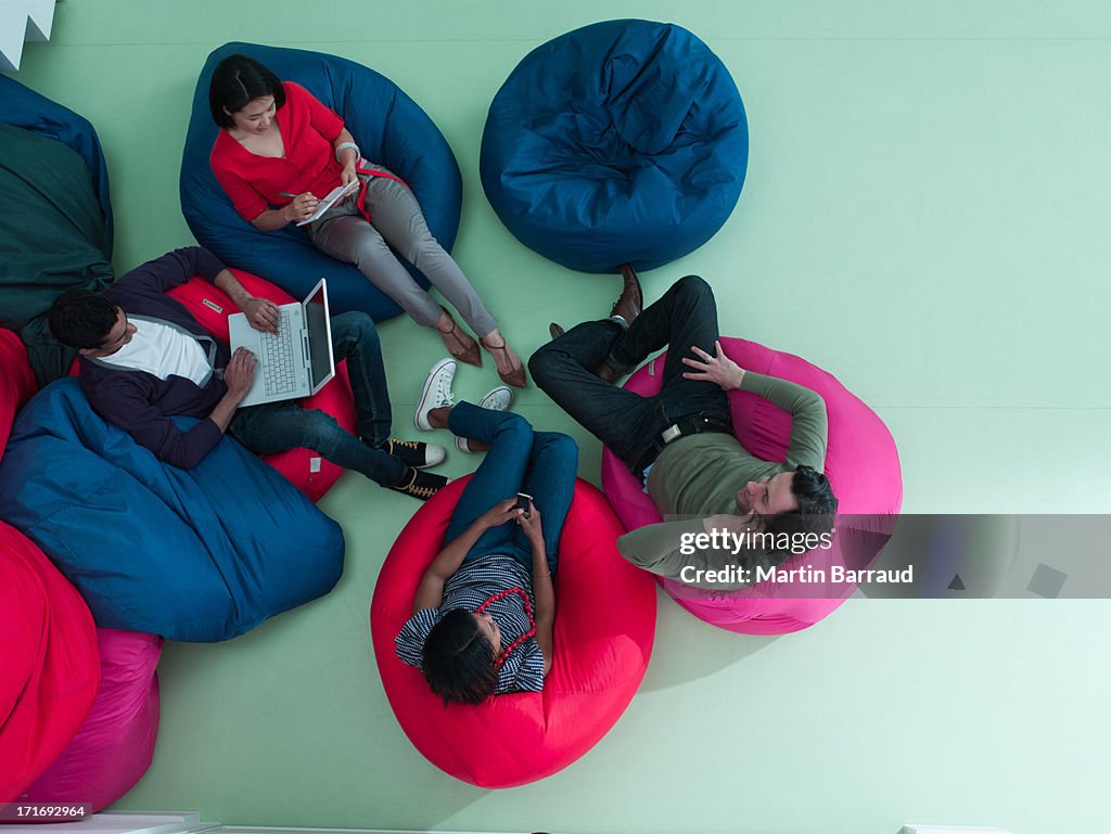 Men and women using laptop and cell phones in bean bag chairs