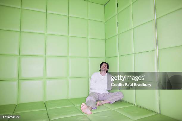 man sitting with legs apart in padded room - madness stock pictures, royalty-free photos & images