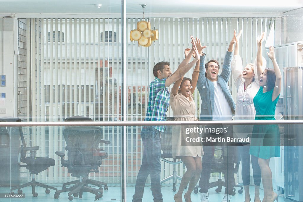 Excited business people with arms raised at window