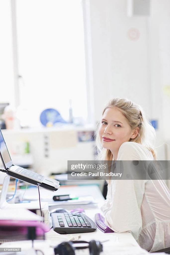 Smiling businesswoman working on laptop at desk in office