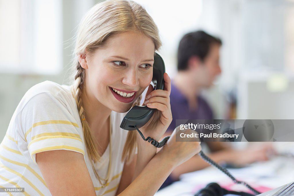 Smiling businesswoman talking on telephone in office