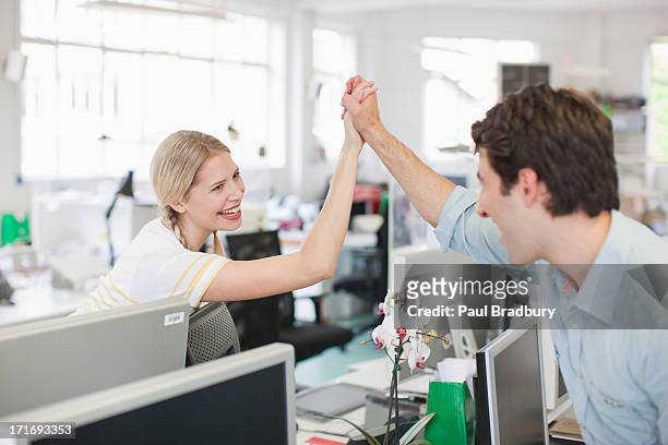 business people holding hand in office - champions day two stockfoto's en -beelden
