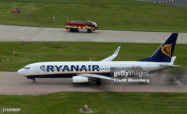 Boeing 757-200 aircraft operated by Ryanair Holdings Plc taxis on a runway as a fire service truck is seen behind at Manchester Airport, operated by...