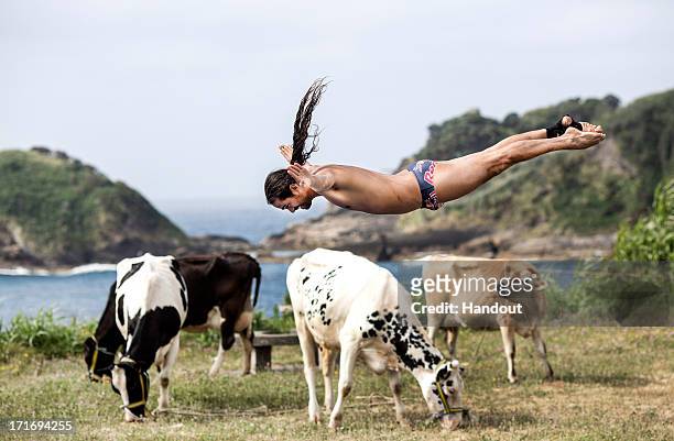 In this handout image provided by Red Bull, Orlando Duque of Colombia has a trampoline session in a field overlooking Islet Franca do Campo after...