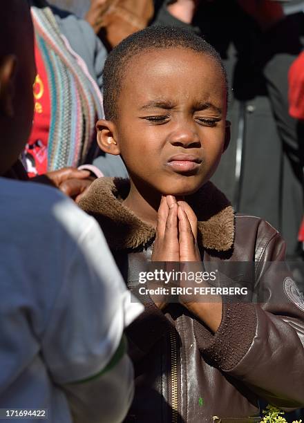 Child prays in front of messages left for Nelson Mandela oustide the Mediclinic Hear hospital on June 28, 2013 in Pretoria. A gravely ill Nelson...