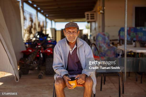 Older man, Adrian, sits in front of a house and poses for a portrait with a cup of tea in his hand on October 04, 2023 in Pia Wadjarri, Australia. A...