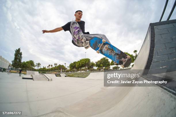 young hispanic man skating at skatepark - rampe stock-fotos und bilder