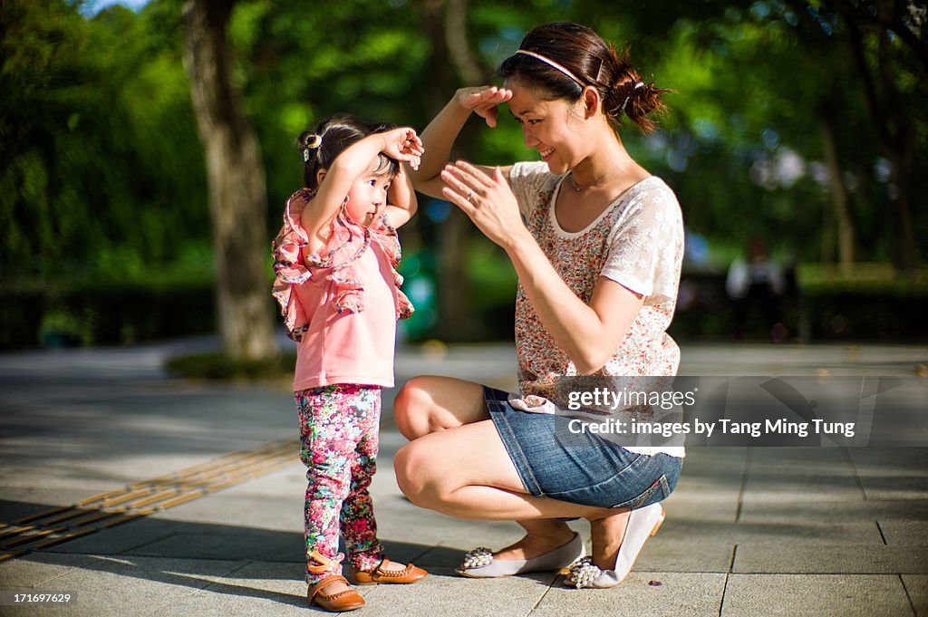 Mom & toddler girl putting their hands over eyes