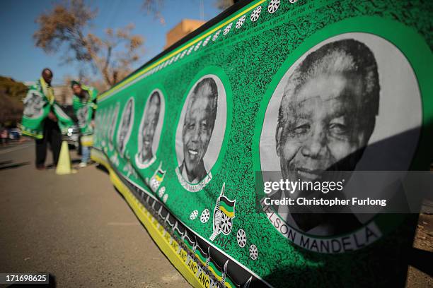 Man unfurls a roll of flags adorned with a photograph of Nelson Mandela outside the Mediclinic heart Hospital on June 28, 2013 in Pretoria, South...