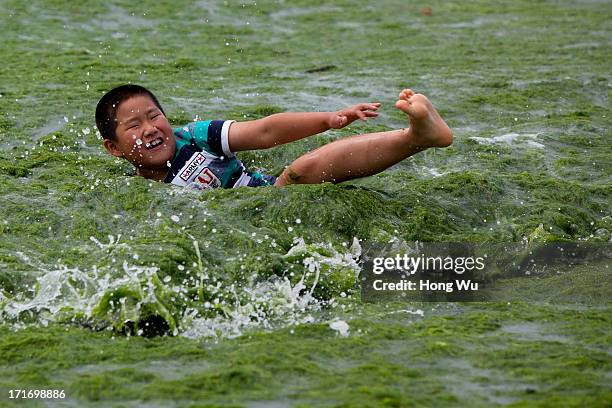 Child plays at a beach covered by a thick layer of green algae on June 28, 2013 in Qingdao, China. A large quantity of non-poisonous green seaweed,...