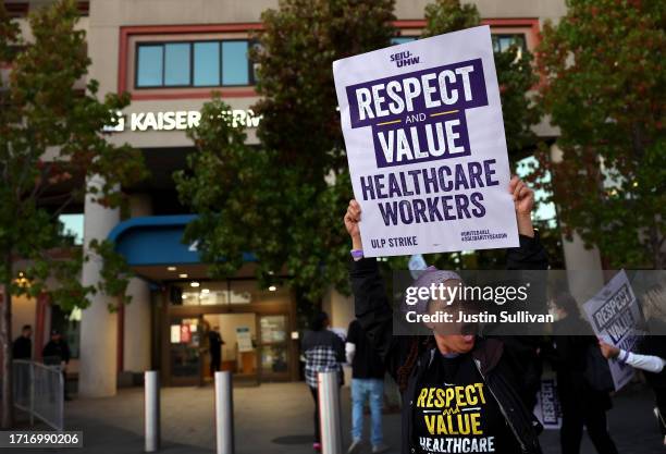 Striking Kaiser Permanente workers hold signs as they march in front of the Kaiser Permanente San Francisco Medical Center on October 04, 2023 in San...