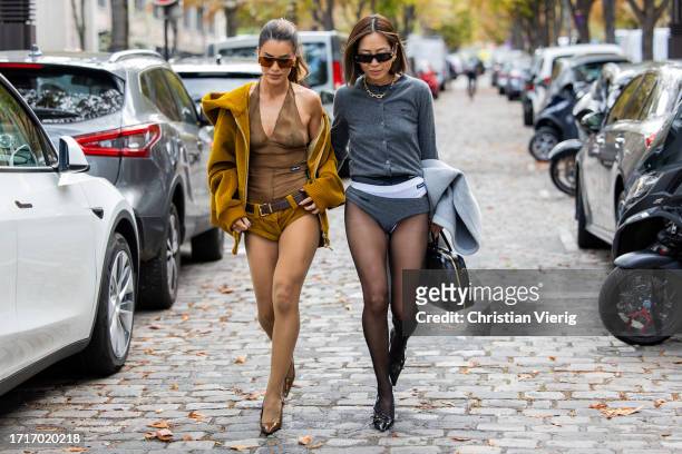 Camila Coelho wears brown transparent top, shorts, brown beige hooded jacket, tights, brown pointed heels & Aimee Song wears grey cardigan, shorts,...