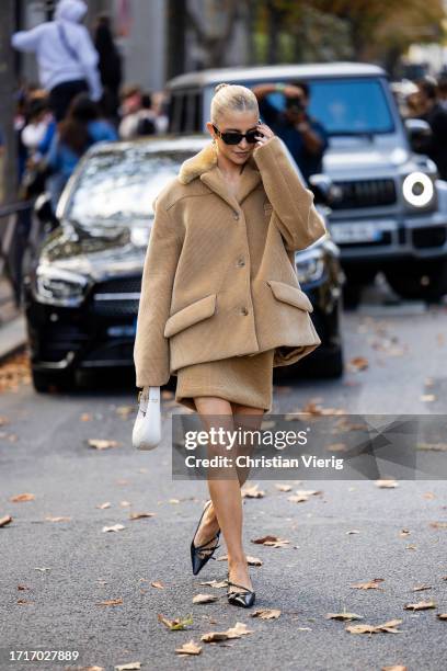 Caroline Caro Daur wears oversized beige jacket, skirt, white bag, sunglasses outside Miu Miu during the Womenswear Spring/Summer 2024 as part of...