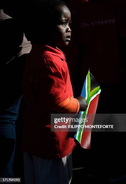 Child holds a South African flag as he stands outside the Medi Clinic Heart hospital in Pretoria on June 28, 2013. A gravely ill Nelson Mandela...