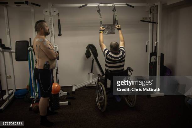 Year-old soldier Andriy, and 52 year-old amputee soldier Valeriy take part in a physical therapy session at a rehabilitation center for soldiers...