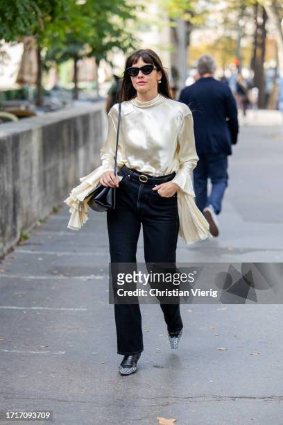Kat Collings Wolf wearsc reme white silk blouse, dark denim jeans, black bag outside Zimmermann during the Womenswear Spring/Summer 2024 as part of...