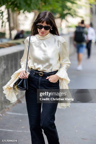 Kat Collings Wolf wearsc reme white silk blouse, dark denim jeans, black bag outside Zimmermann during the Womenswear Spring/Summer 2024 as part of...