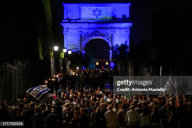 People hold banners and wave Israeli flag during a Pro-Israel demonstration next to the Arco di Tito, on October 9, 2023 in Rome, Italy. On October...