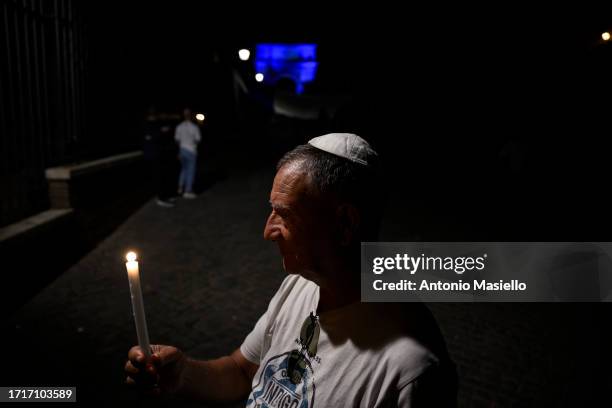 Man holds a lit candle during a Pro-Israel demonstration next to the Arco di Tito, on October 9, 2023 in Rome, Italy. On October 7, the Palestinian...