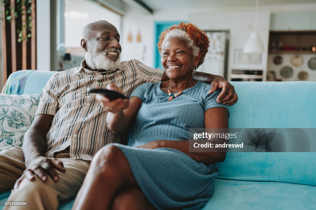 Portrait senior couple watching TV in living room