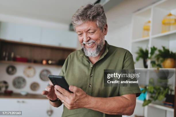 portrait of a senior man using smartphone at home - one man only imagens e fotografias de stock