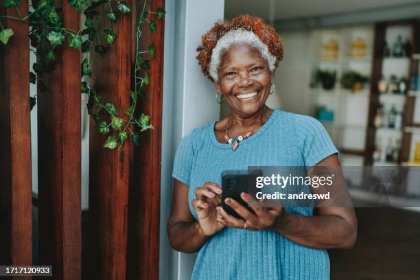 retrato mulher sênior usando smartphone sorrindo - mulheres maduras - fotografias e filmes do acervo