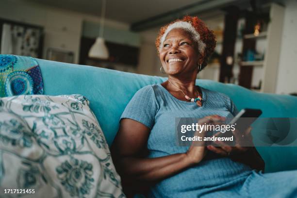 portrait senior woman using smartphone smiling - silver surfer stock pictures, royalty-free photos & images