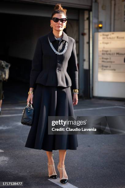 Giovanna Battaglia Engelbert wears a black jacket, black midi skirt, nude heels, crystals necklace and Dior black bag, outside Sacai, during the...