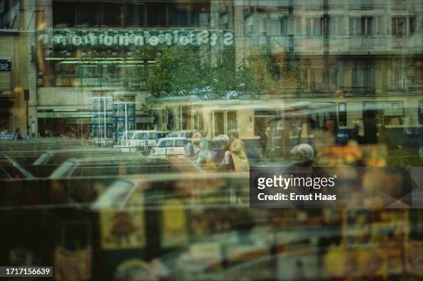 Multiple reflections of a busy street with cars, trams and a motorcyclist, in a window, West Germany, circa 1975.