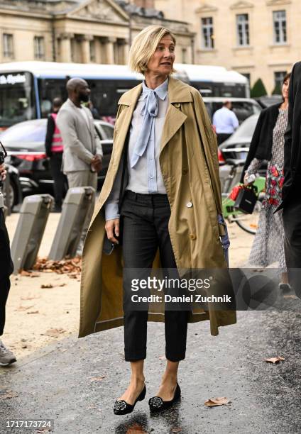 Guest is seen wearing a tan trench coat, blue blouse, black jeans and black outside the Chanel show during the Womenswear Spring/Summer 2024 as part...