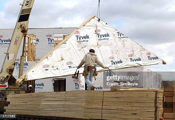 Carpenter walks across a stack of lumber as a roof truss is lifted towards a new single-family home in a new subdivision January 9, 2003 in Glenview,...