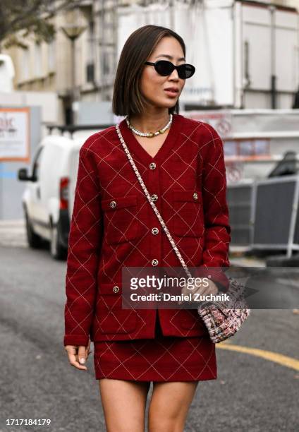 Aimee Song is seen wearing a red tweed Chanel jacket and skirt, tweed Chanel bag and black sunglasses outside the Chanel show during the Womenswear...