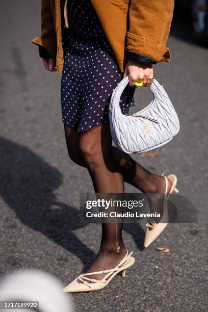 Emili Sindlev wears a beige top and cardigan, blue polka dot mini skirt, brown Carhartt jacket, gret Miu Miu bag and beige kitten heels, outside Miu...