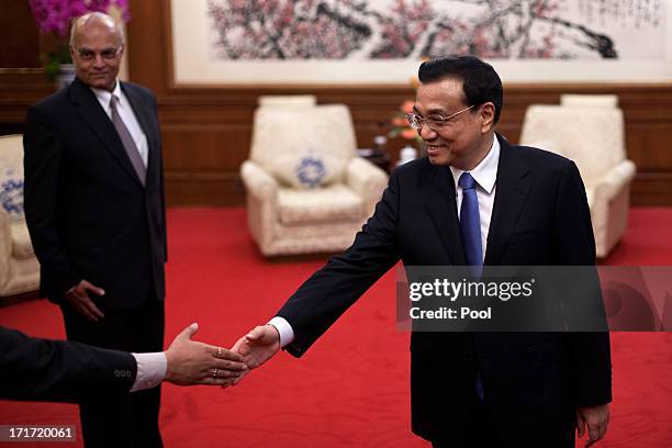 Chinese Premier Li Keqiang shakes hands with members of a visiting Indian delegation while India's National Security Adviser Shivshankar Menon looks...