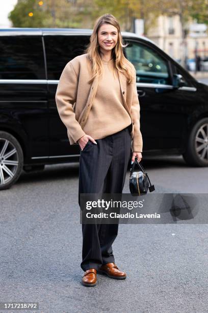 Zita d'Hauteville wears a beige Miu Miu sweater with matching cardigan, black trousers and black Miu Miu bag, outside Miu Miu, during the Womenswear...
