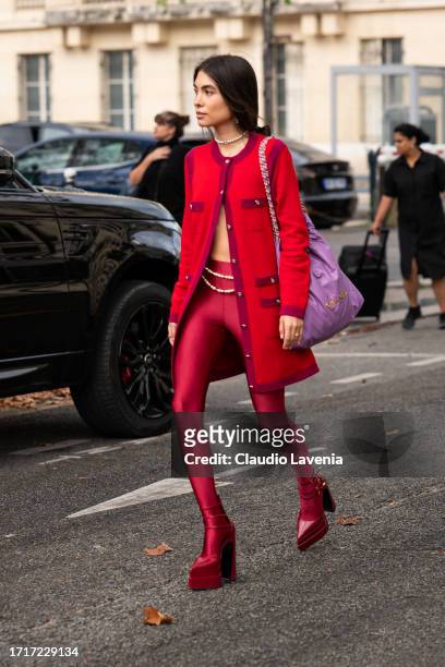 Fer Millan wears a red Chanel long cardigan, red tights, red platform heels, purple Chanel bag, outside Chanel, during the Womenswear Spring/Summer...