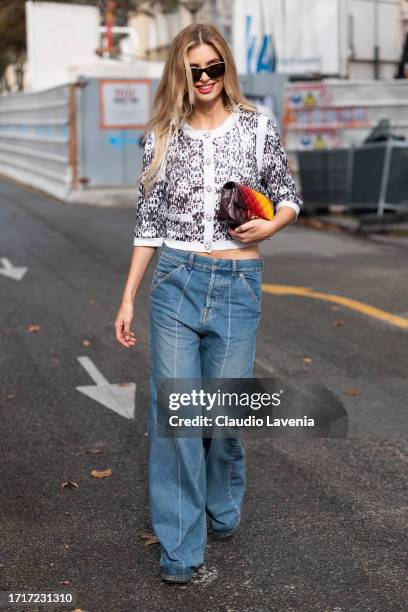 Xenia Adonts wears a white sequins Chanel cardiigan, wide leg jeans, brown and yellow Chanel bag, outside Chanel, during the Womenswear Spring/Summer...