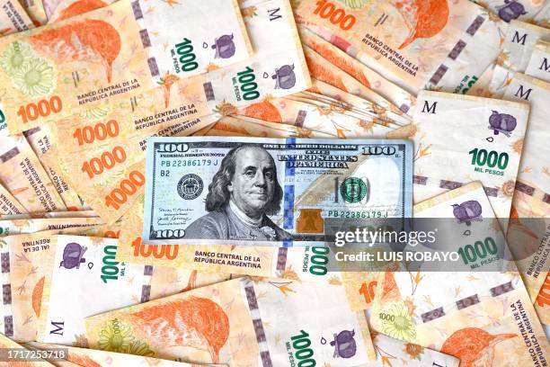 This illustration picture shows a 100 USD banknote on top of Argentinian pesos, in Buenos Aires on October 10, 2023. The US dollar broke through the...