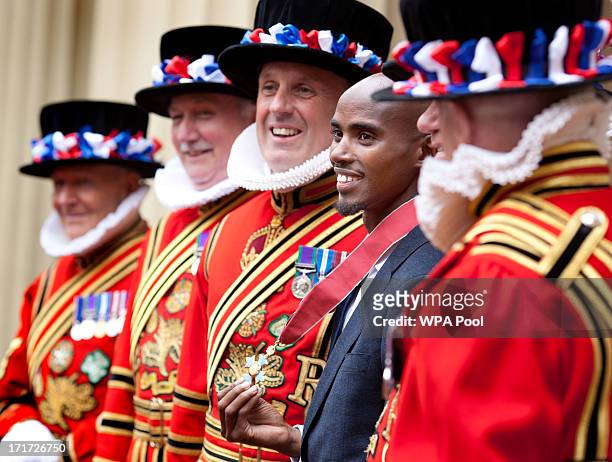 Double Olympic Gold Medal winning athlete Mo Farrah poses with beefeaters as he wears his CBE after he received the award from Prince Charles, Prince...