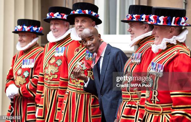 Double Olympic Gold Medal winning athlete Mo Farrah poses with beefeaters as he wears his CBE after he received the award from Prince Charles, Prince...