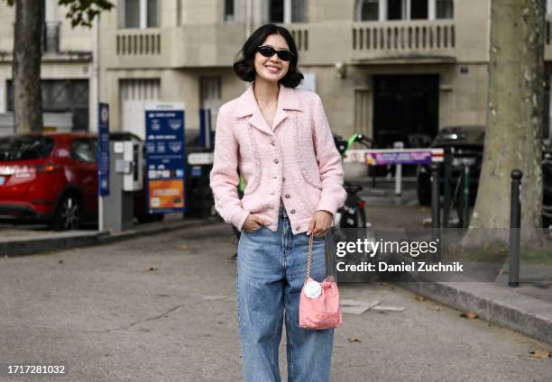 Guest is seen wearing a pink Chanel jacket, blue jeans, pink gold chain bag outside the Chanel show during the Womenswear Spring/Summer 2024 as part...