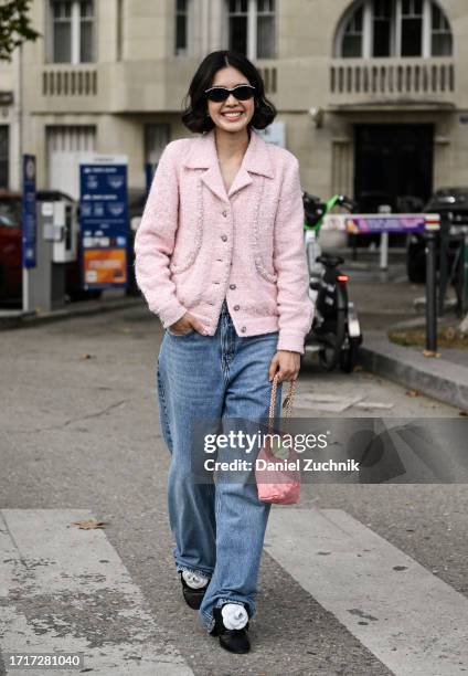 Guest is seen wearing a pink Chanel jacket, blue jeans, pink gold chain bag and black and white floral shoes outside the Chanel show during the...