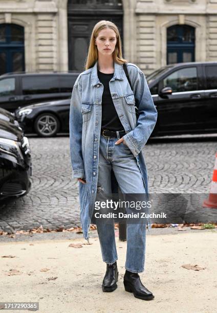 Model Abby Champion is seen wearing a denim coat, black top, light blue jeans and black belt and black boots outside the Chanel show during the...