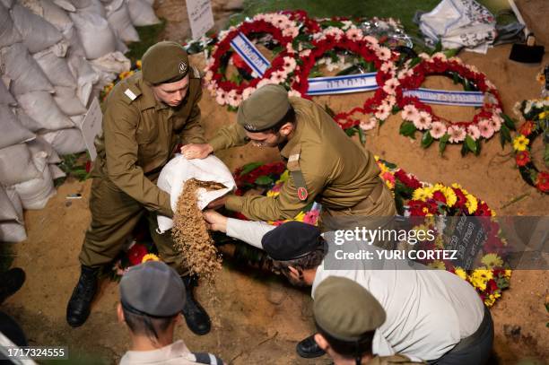 Israeli army soldiers drop dirt on the grave of their comrade Noam Elimeleh Rothenberg at Mount Herzl Cemetery during his funeral in Jerusalem on...