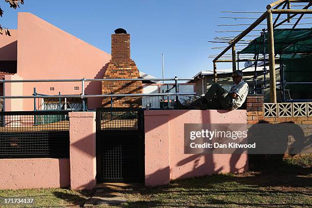 Man sits on a wall as the media await the arrival of Former wife of Nelson Mandela Winnie Madikizela-Mandela outside Nelson Mandela House in Soweto...