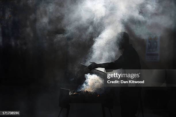 Man prepares a barbeque as the media await the arrival of Former wife of Nelson Mandela Winnie Madikizela-Mandela outside Nelson Mandela House in...