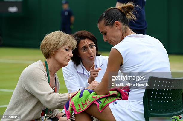 Flavia Pennetta of Italy receives treatment during her Ladies' Singles third round match against Alize Cornet of France on day five of the Wimbledon...