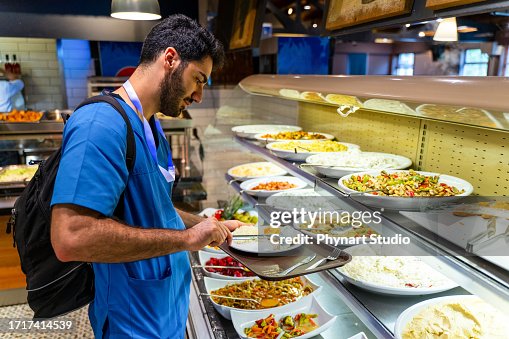 Man in medical scrubs eating at a buffet style cafeteria Man in medical scrubs eating at a buffet style cafeteria